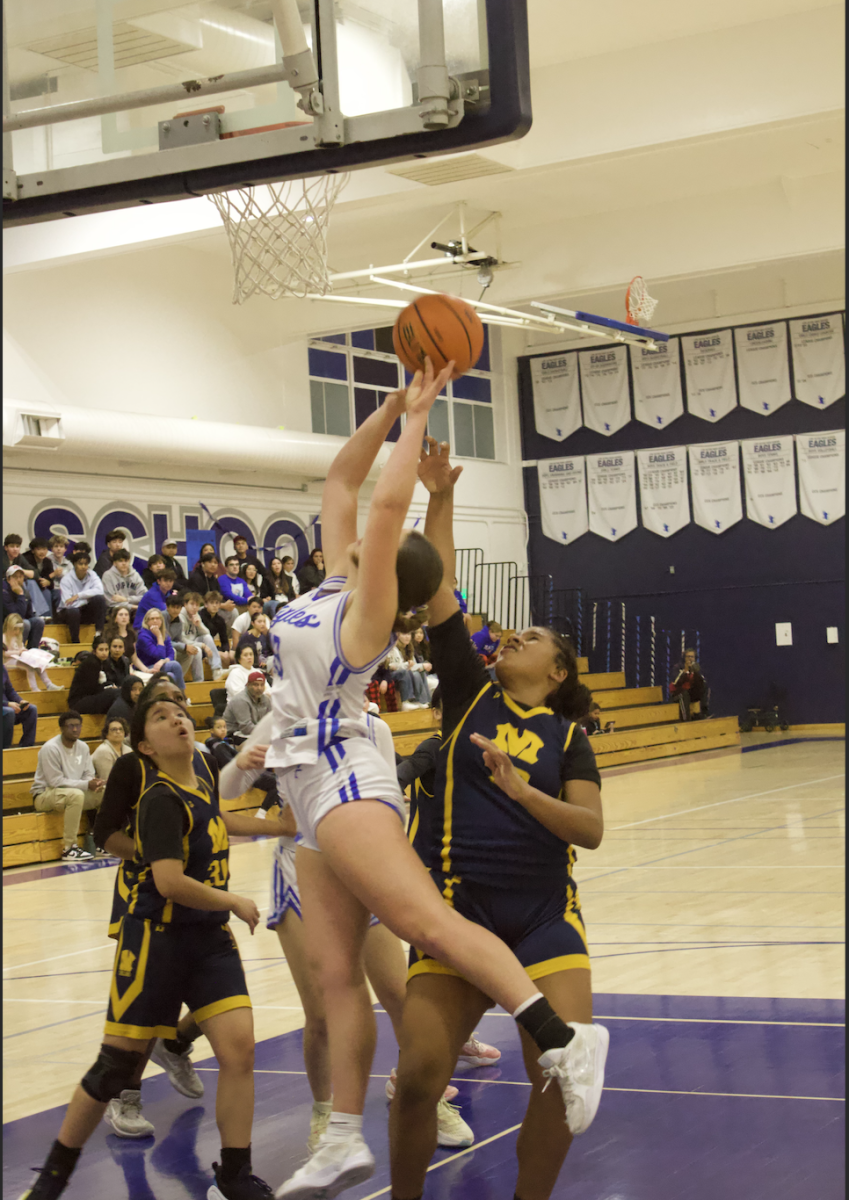 A Los Altos varsity girls basketball player attempts to score against the Milpitas High School Trojans.